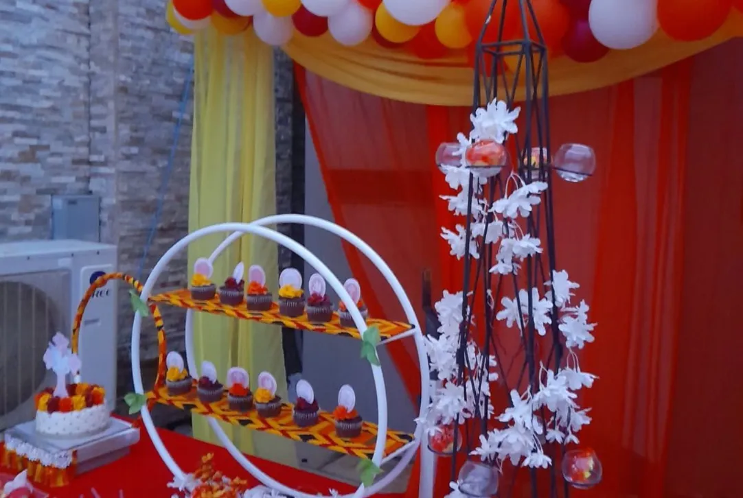 Dessert table with red and yellow drapery, cupcake stand and balloon garland