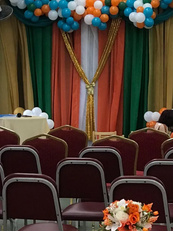 Stage with gold, orange, green and white drapery and balloon garland