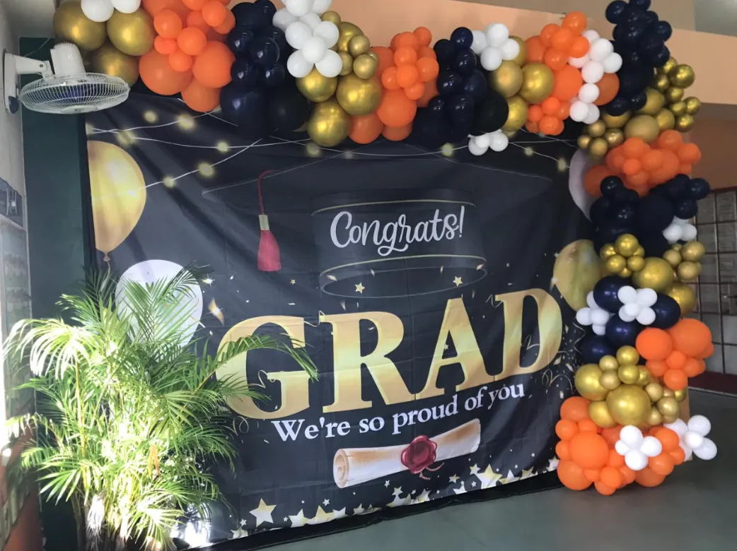 Orange, gold, navy and white balloon garland around a graduation backdrop